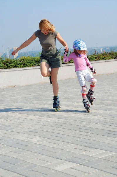 Mother teaching daughter rollerblading