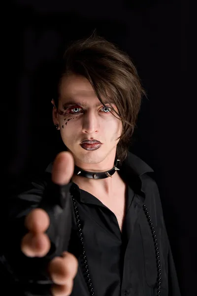 Gothic boy with artistic make-up pointin