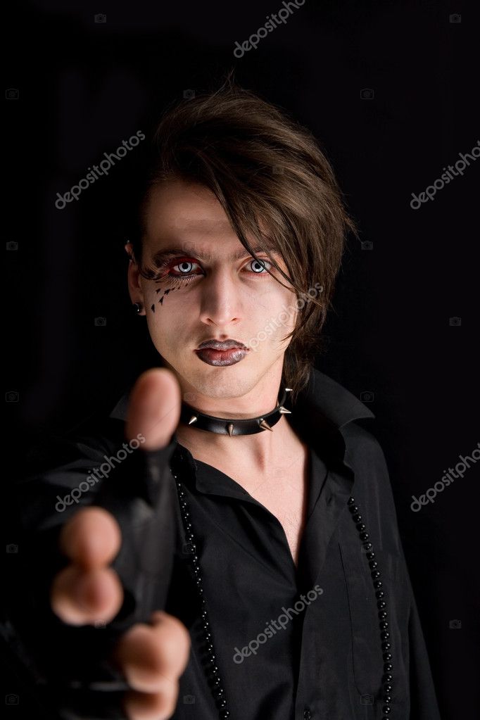 Gothic boy with artistic makeup pointing his hand as a gun 