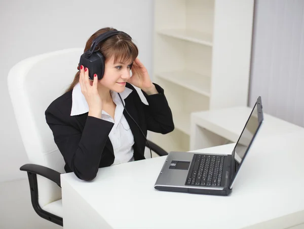 Girl listens to music by means of laptop