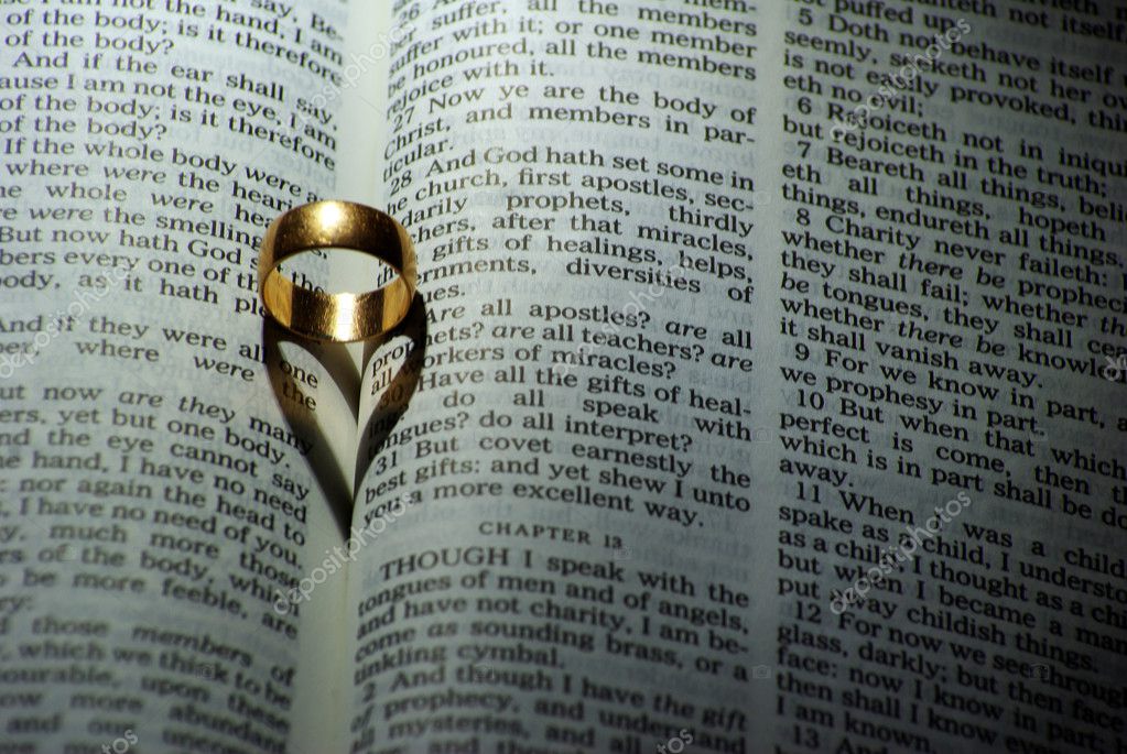 Wedding ring and heart shaped shadow over a Bible