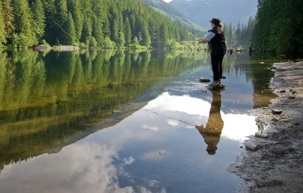 Woman fly fishing at a lake