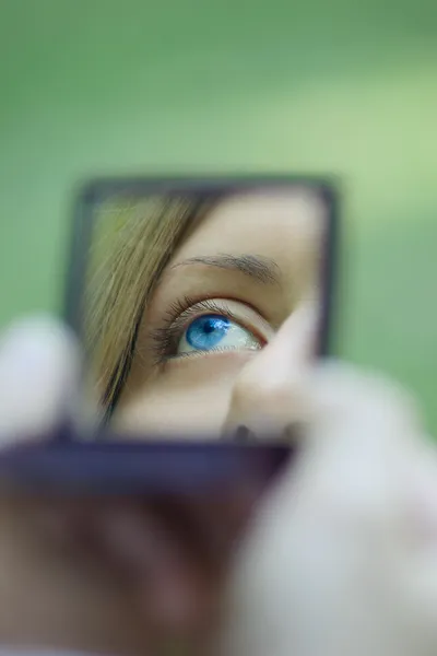 Female eye reflected in a pocket mirror