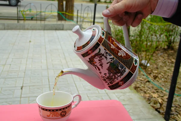 Pouring green tea in a teacup