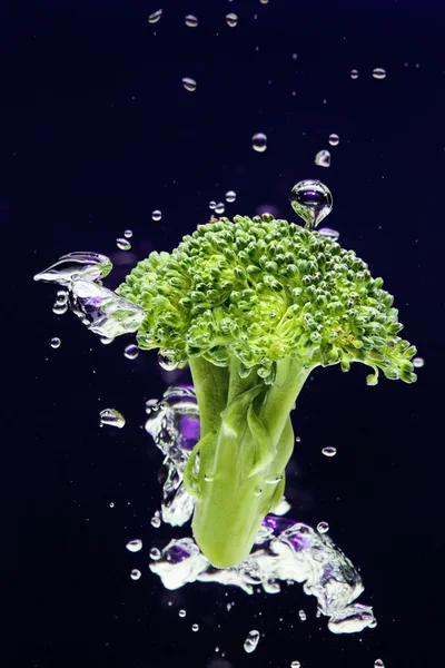 Green broccoli falling in water