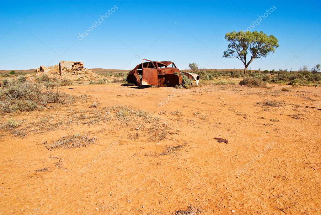An old car rusts away in the desert in the australian outback