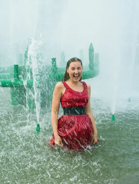 Girl in wet clothes in a city fountain