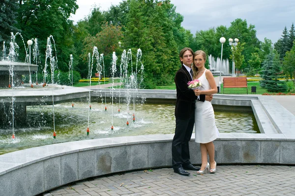 Bride and groom against urban fountain