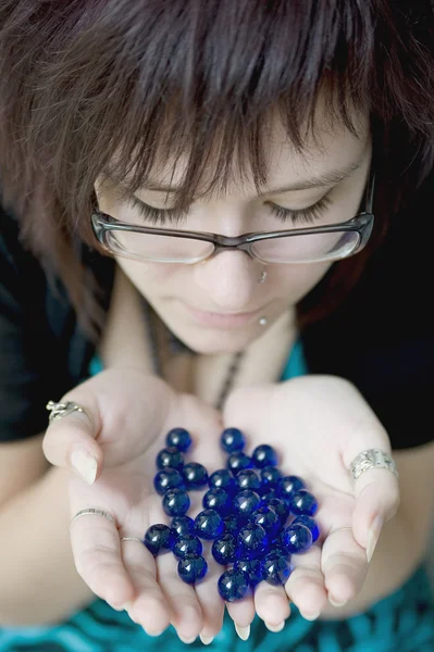 A young girl looks at the blue beads (glass beads) in the palms