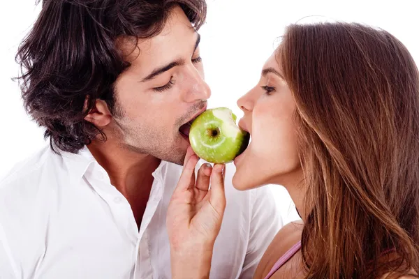 Couple playfully biting green apple