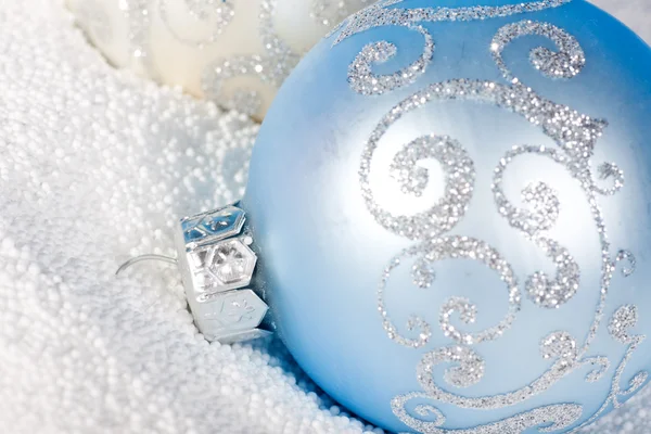 Tender blue Christmas bauble on to snow.
