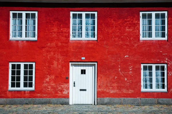 Red wall with white windows and door
