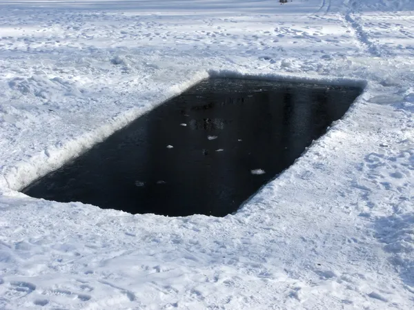 Ice hole in frozen lake