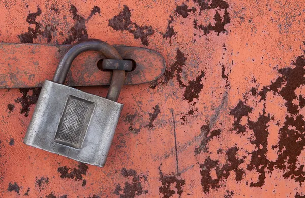 Old padlock on rusty metal door