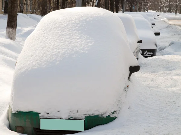 Snow covered cars in row