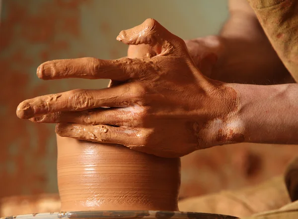 Hands of potter do a clay pot