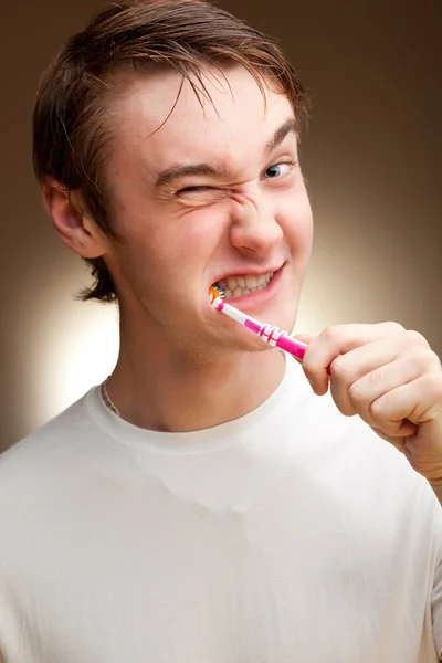 A funny young man cleans teeth. Toned.
