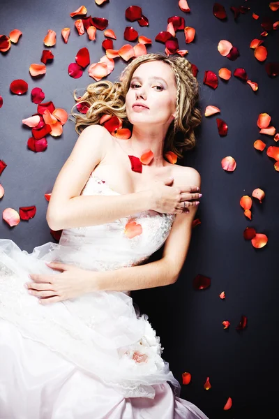 Bride lying among rose petals