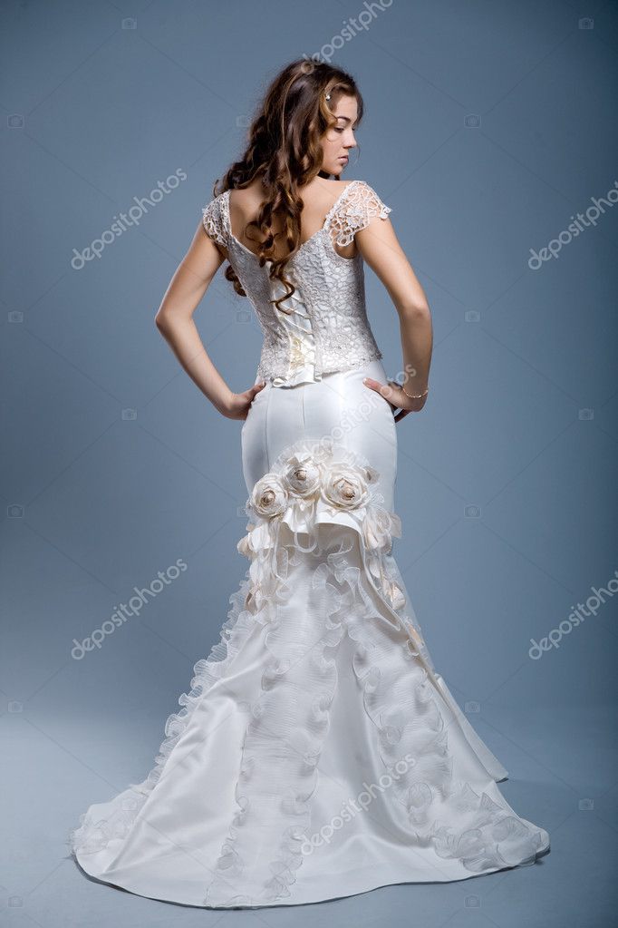  long hair wearing luxurious wedding dress over gray studio background