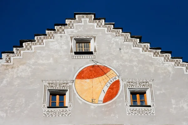 Red and orange sundial on house wall