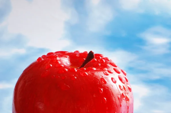 Apple with water drops against the sky