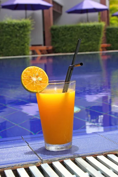 Orange cocktail stands on edge of pool