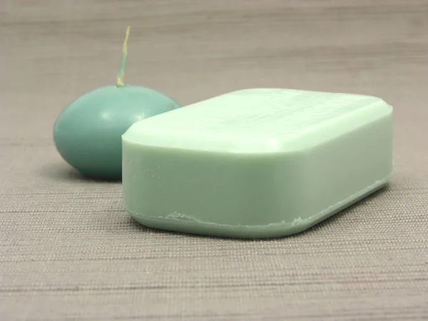 Green soap and green candle on a gray b