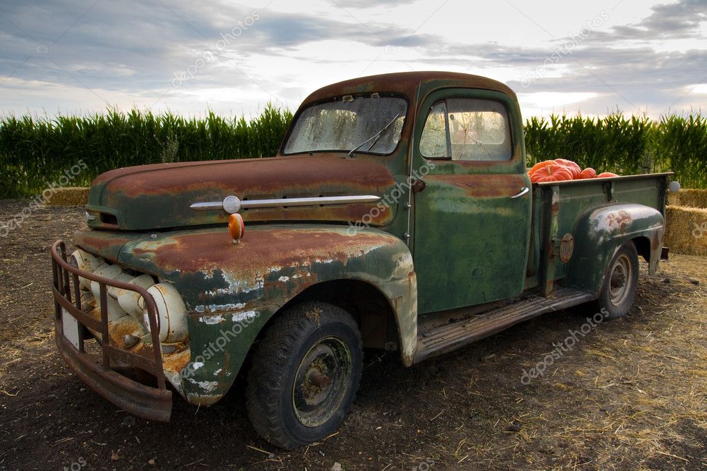 Rusty old truck fit with pumpkin sits alone in the field on a farm