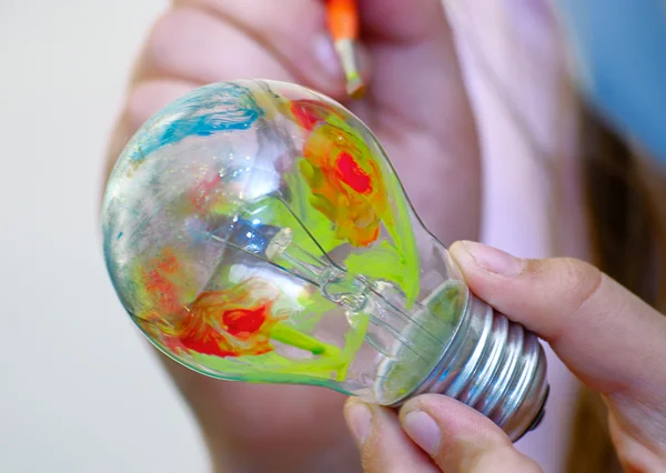 Multicolor painting light bulb in hand