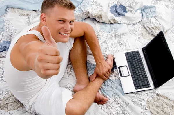 Young man with thumbs up and laptop