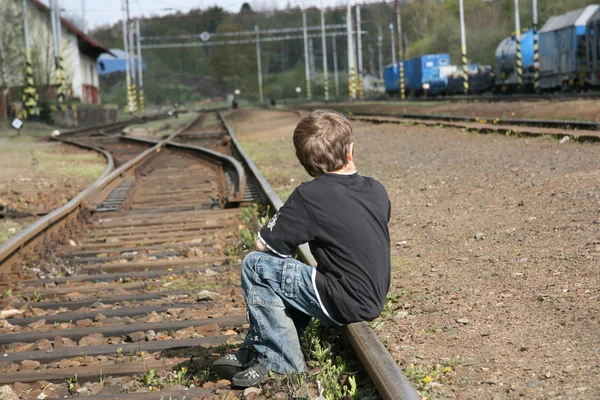 Boy sitting on rail track
