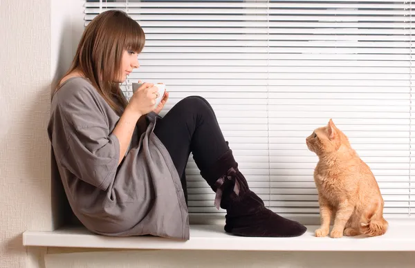 Girl with a cup of cappuccino and a cat