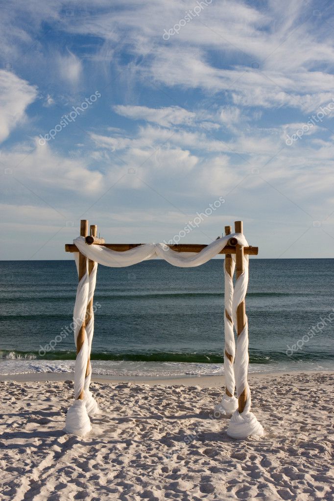 A beach wedding arch is erected on the sand by the sea