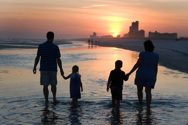 Young Family Silhouetted By Sunset