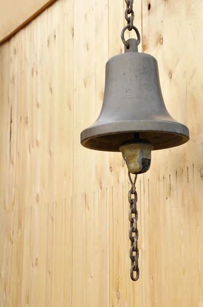 Bronze bell at wooden wall