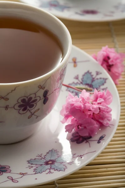 Cup of tea and flowers over bamboo mat