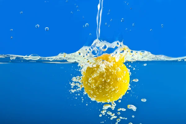 Lemon splashing into blue water