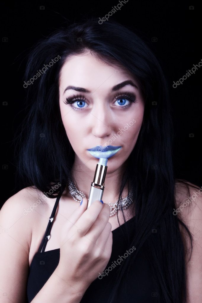 Beautiful young woman painting lips in blue color Beautiful young woman painting lips in blue color