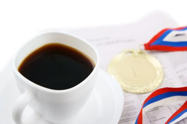 Gold medal and coffee cup on newspaper