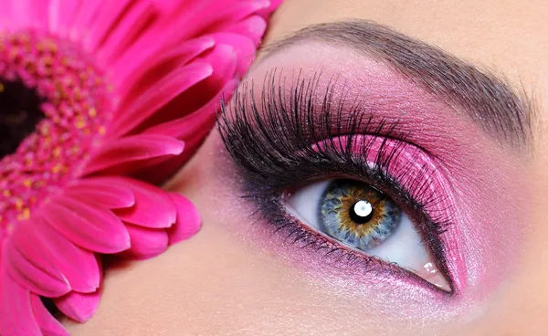 Woman eye with pink make-up and flower