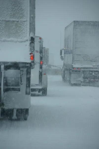 Trucks on winter highway during snowstorm