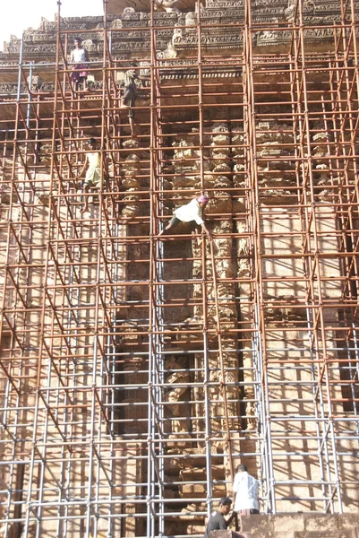Workers climb iron scaffolding