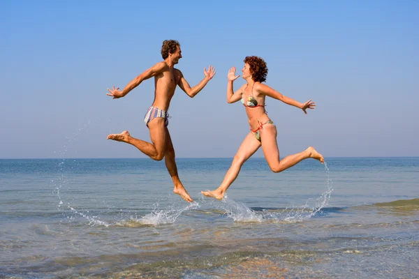 Man and woman jumping in sea