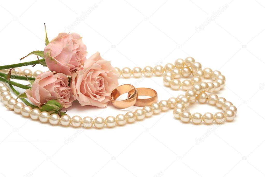 Two golden rings pearls and flowers on white background