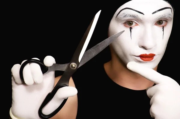 Mime with scissors on black background