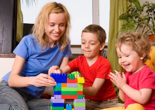 Happy mum with children plays cubes