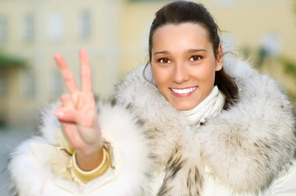 Girl in fur coat shows victory