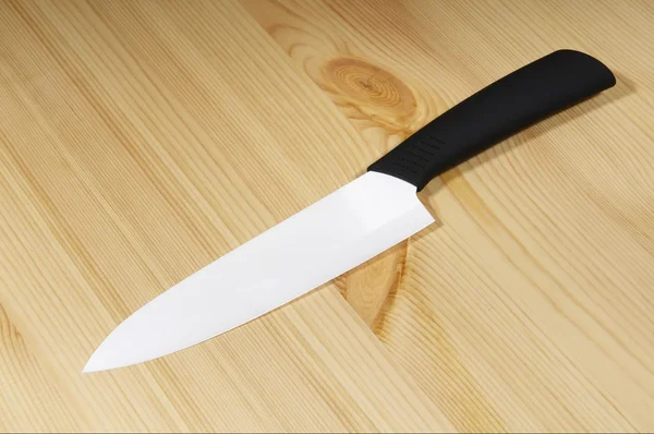 White ceramic knife on wood background