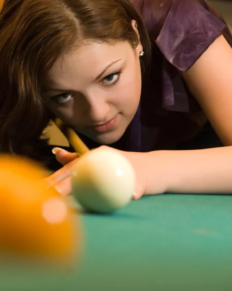 Young woman playing billiards