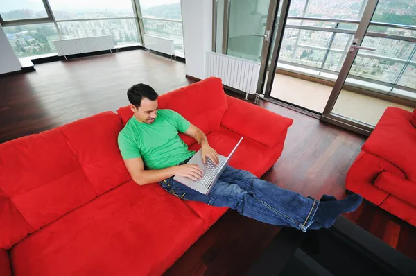 Man relaxing on sofa and work on laptop